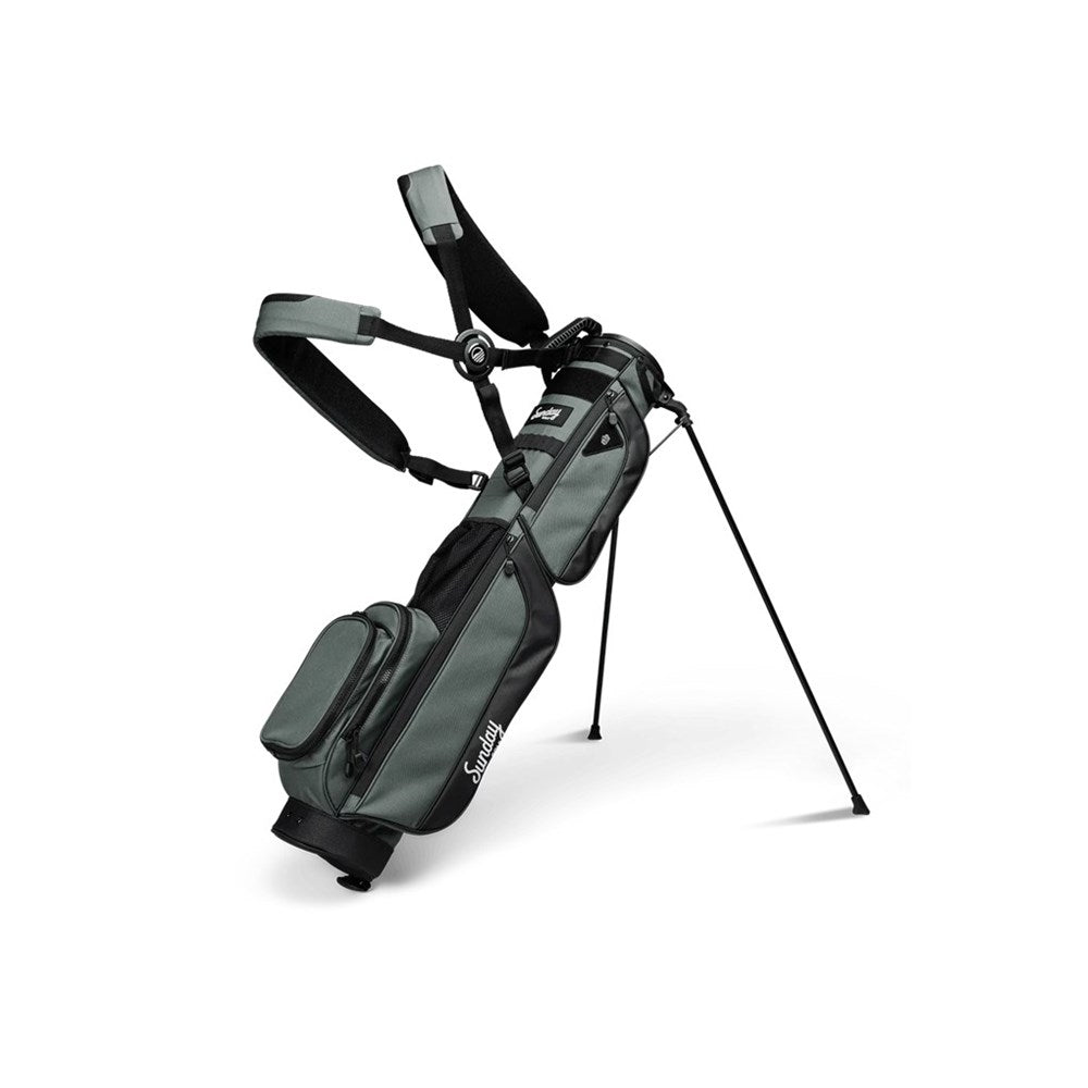 A gray golf bag with a stand system deployed, featuring multiple pockets and a shoulder strap.