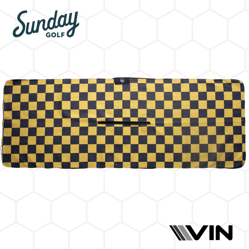 A black golf towel with a yellow checkered pattern on the lower right corner, featuring the 'Sunday Golf' logo in yellow and white, displayed on a hexagonal background.